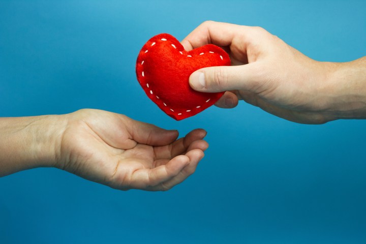 Man hand puting the red soft heart in woman hand