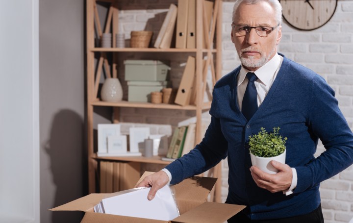 Sad dismissed office worker putting away his things
